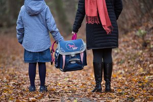 Ein kind und ein Erwachsener tragen den Schulranzen.