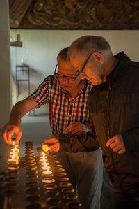 Zwei Personen zünden in der Kirche eine Kerze an.