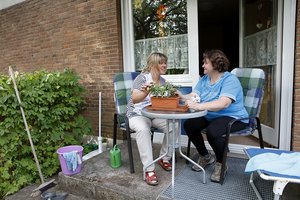 Zwei Frauen unterhalten sich und pflegen beizu eine Blume.