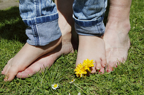 Kinder- und Erwachsenenfüße auf dem Gras.